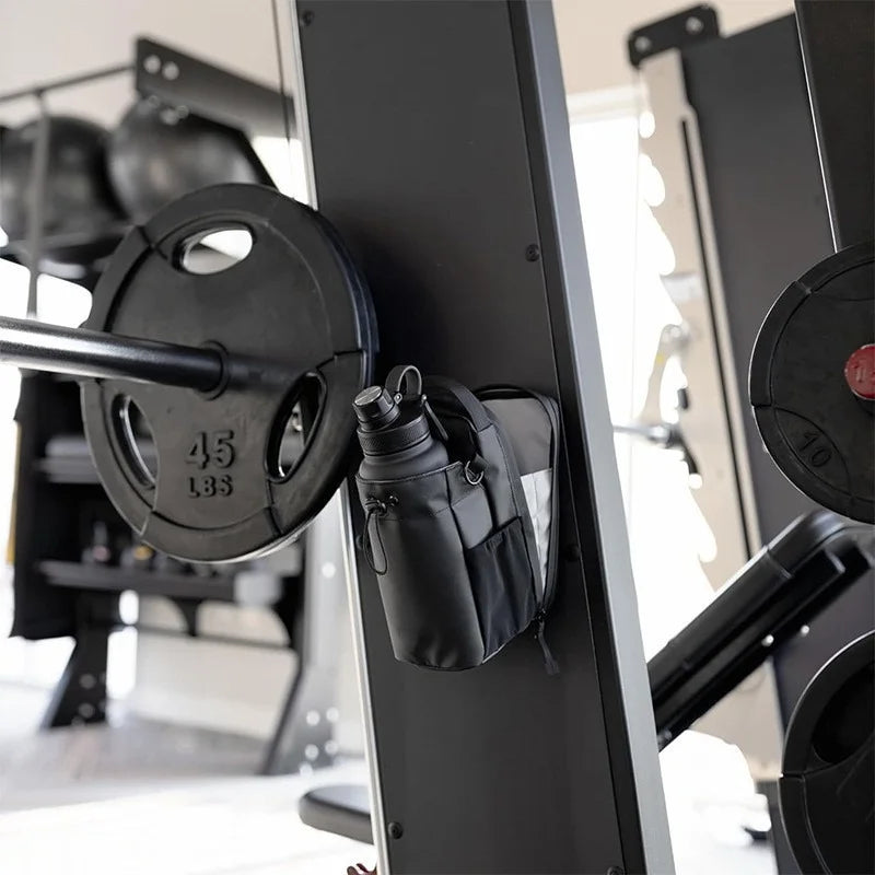 Black magnetic gym bag attached to gym equipment frame showing magnetic mounting feature with water bottle